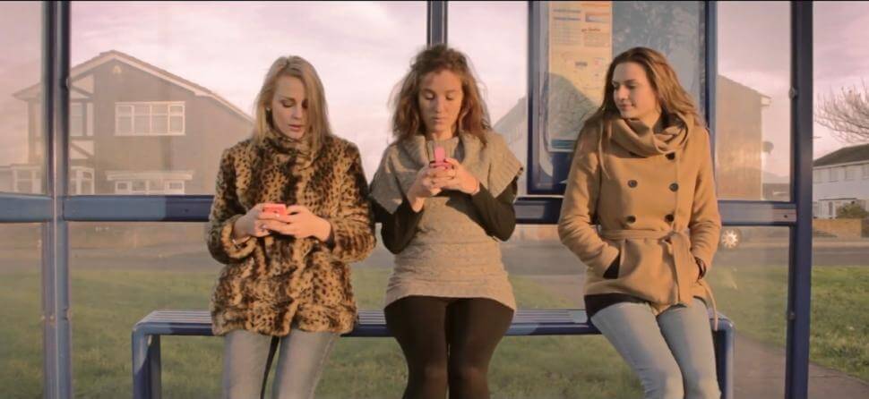 жінки на зупинці користуються мобільними телефонами