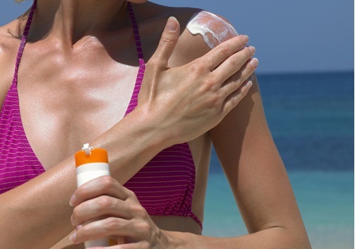 жінка мастись плечі сонцезахисним кремом