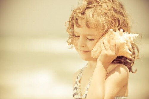 дитина тримає біля вуха мушлю