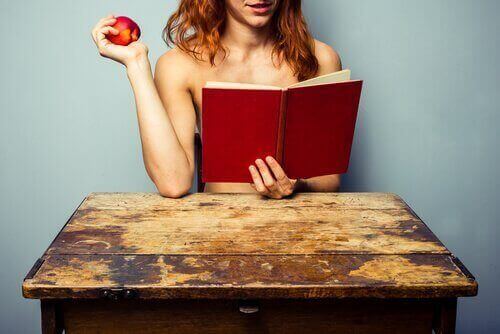 жінка читає книгу та їсть яблуко