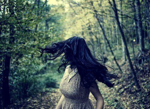 дівчина біжить через ліс, оглядаючись та відчуваючи страх