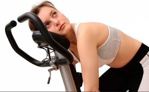 втомлена жінка на велотренажері