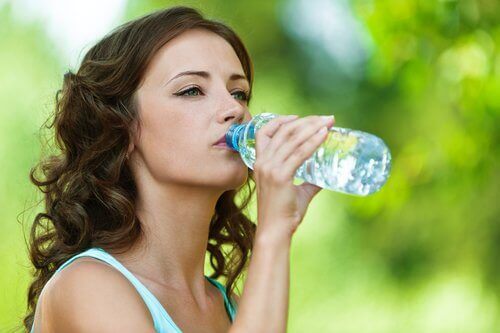 дівчина п'є воду з пластикової пляшки